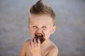 Child eats chokolate with full stength on a beach