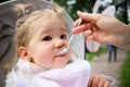 Child eats food from a spoon in the park