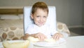 The child eats a melon, sitting at the table, in slow motion. The concept of healthy baby food.