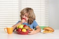 Child eats strawberry, organic fruits. Kid preteen boy in the kitchen at the table eating vegetable and fruits during Royalty Free Stock Photo