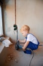 Child with electric power tool standing against the wall. Royalty Free Stock Photo