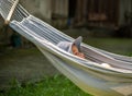 Child, elementary school age girl lying in a hammock outdoors, resting, bored kid lying down outside, funny shot, side view, one