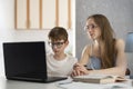 Child is engaged online with his mother and does homework on the computer. Young tutor works with student.Home schooling