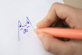 Child erasing drawing with erasable pen on paper sheet against beige background, closeup