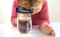 The child examines the water under a magnifying glass. Selective focus. Royalty Free Stock Photo