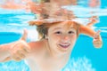 Child face underwater with thumbs up. Young boy swim and dive underwater. Under water portrait in swim pool. Child boy Royalty Free Stock Photo