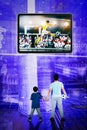 Child and father look at a player soccer on monitor