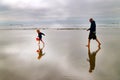 Child and Father Running on Beach with Reflection in Water