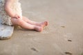 Child feed on a beech sand. baby`s bare legs