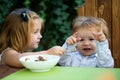 Child feeding baby with spoon. Two little children, adorable toddler girl and funny baby boy, eating together, sister