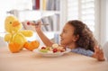 Child feeding, teddy bear and food at home with happiness and wellness meal with a smile. House, nutrition and young