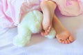 Child feet under the blanket and soft fluffy toy