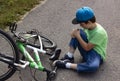 Child fell off bicycle. Boy keeps self for bruised knee Royalty Free Stock Photo