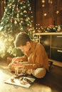 Child repairing a toy near the Christmas tree