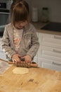 Child flattening some pizza dough with a rolling pin