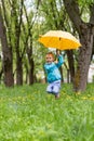 The child `flies` on an umbrella against the background of a meadow with blooming dandelions.