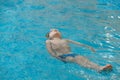 Child floating on the back in the water in indoor swimming pool