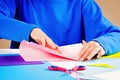 Kid folding colored paper and making origami.