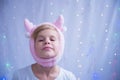 The child is fooling around. A girl posing in a New Year's hat in the form of deer horns. Preparing for the new year and