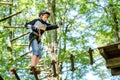 Child in forest adventure park. Kid boy in helmet climbs on high rope trail. Agility skills and climbing outdoor Royalty Free Stock Photo