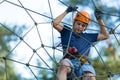 Happy child, healthy teenager in helmet enjoys activity in a climbing adventure rope park