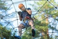 Child in forest adventure park. Kid in orange helmet and blue t shirt climbs on high rope trail. Agility skills Royalty Free Stock Photo