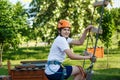 Child in forest adventure park. Kid in orange helmet and white t shirt climbs on high rope trail. Agility skills and climbing