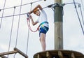 Child in forest adventure park. Kid in orange helmet and white t shirt climbs on high rope trail. Agility skills and climbing Royalty Free Stock Photo