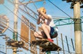 Child in forest adventure park. Kid in orange helmet and white t shirt climbs on high rope trail. Agility skills and climbing Royalty Free Stock Photo