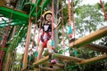 Child in forest adventure park. Kids climb on high rope trail. Agility and climbing outdoor amusement center for children. Little