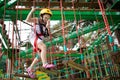 Child in forest adventure park. Kids climb on high rope trail. Agility and climbing outdoor amusement center for children. Little