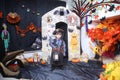 A child in the form of a witch on a broomstick, poses against the backdrop of pumpkins on Halloween holiday . Boy is Royalty Free Stock Photo