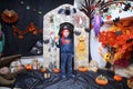 A child in the form of a witch on a broomstick, poses against the backdrop of pumpkins on Halloween holiday . Boy is