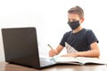 A child in front of a computer. Boy in an antibacterial mask is doing homework. Distance learning in quarantine