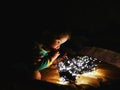 Child and garland in the dark. little child holds shiny christmas lights indoors close dark background. Portrait of a