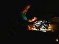 Child and garland in the dark. little child holds shiny christmas lights indoors close dark background. Portrait of a happy kid