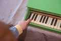 The child gently presses the piano knob with his index finger. A six-year-old boy in blue pajamas plays a child`s toy piano Royalty Free Stock Photo