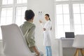 Ophthalmologist testing vision of little child and pointing at eye chart on wall