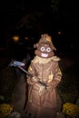 Child in giant turd Halloween costume with scarecrow hat and burlap robe carrying a pickaxe on doorstep trick or treating