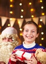 Child girl accepting gifts from Santa near decorated xmas tree with lights, they talking and smiling - Merry Christmas and Happy Royalty Free Stock Photo