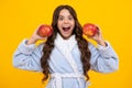 Child girl with apple over isolated yellow studio background. Tennager with fruit. Portrait of happy funny smiling