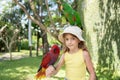 child girl with beautiful macaw parrot in her shoulder in the zoo, Bali, Indonesia