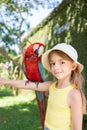 child girl with beautiful macaw parrot in her shoulder in the zoo, Bali, Indonesia