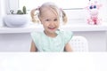 Child girl blonde sits at a white table Royalty Free Stock Photo