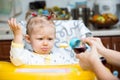 Child girl with bottle with infant formula on kitchen.