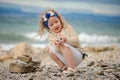 Child girl building stone tower on the beach