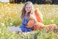 Child girl in camomile field with teddy bear Royalty Free Stock Photo