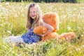 Child girl in camomile field with teddy bear Royalty Free Stock Photo