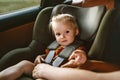 Child girl in a car safety seat and mother fastens belt family lifestyle road trip vacations