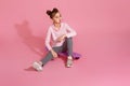 child girl with chewing gum sitting on skateboard Royalty Free Stock Photo